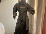 a statue of a monk on a table next to a candle