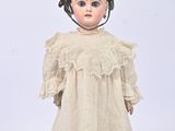 an old doll with a white dress and brown shoes on a white surface
