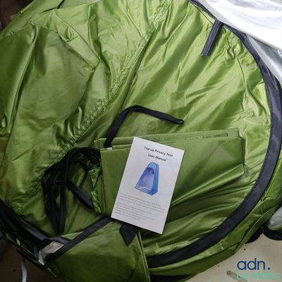 a green backpack with a tag on it sitting on a bed
