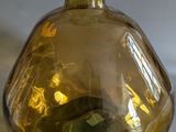 a yellow glass vase with a green apple inside of it