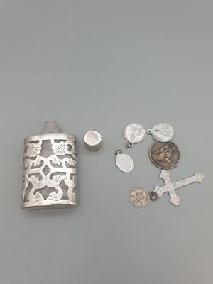 une flasque en argent ornée d'une croix, d'une pièce de monnaie et d'une autre croix