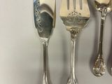 five silver spoons and two silver spoons on a white surface
