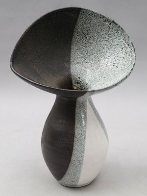 un vase noir et blanc posé sur une surface blanche
