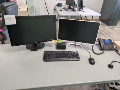 two computer monitors and a keyboard on a desk