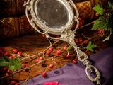 a mirror and a rose sitting on a purple cloth
