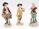 three figurines of a man and a woman holding a basket
