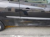 une voiture noire endommagée, garée sur le bord de la route