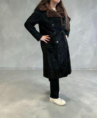 La jeune fille porte un manteau noir et un pantalon noir.