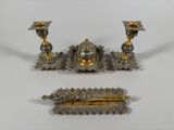 three pieces of silver and gold jewelry on a white surface