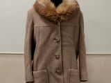 coat on a mannequin stand with a fur collar