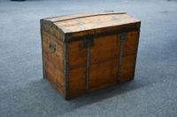 Grande malle à couvercle bombé en bois et renforts de métal.