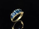 une bague en or sertie de saphirs bleus et de diamants sur un fond noir