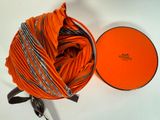 une boîte orange posée sur une surface blanche, avec une pelote de laine à côté