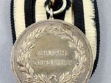 an old medal with a ribbon around it on a white surface