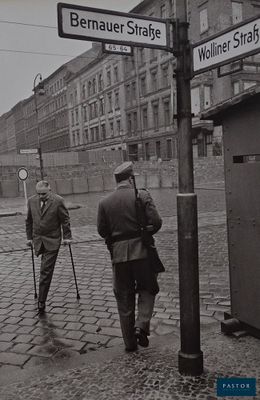 black and white photograph of two men walking down a cobblestone street