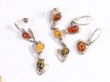 three pairs of silver and amber earrings on a white surface