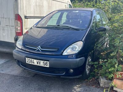 une petite voiture bleue garée devant un garage