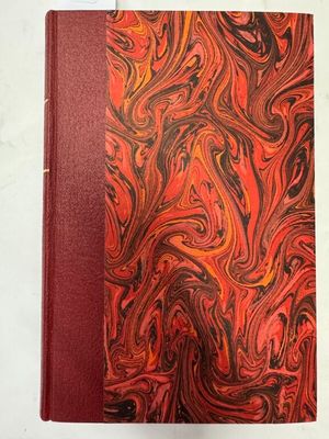 un livre orange et noir avec une couverture rouge posée sur une surface blanche