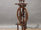 an old spinning wheel on a wooden stand on a wooden floor