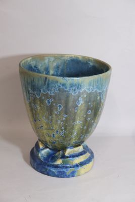 a blue and green vase sitting on a white surface