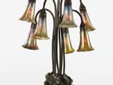 une lampe en bronze et en verre, ornée de cinq fleurs, posée sur un socle