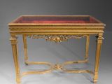 a gold and red table with a glass top on a grey background