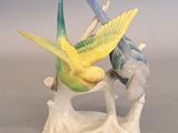 two figurines of birds sitting on a tree branch