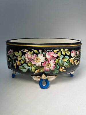 a black bowl with flowers painted on it on a stand