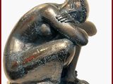 une statue représentant un homme assis par terre, la tête entre les mains