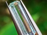 quelqu'un tient une pince dans laquelle est sertie un cristal vert