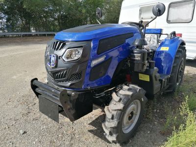 a blue tractor parked next to a trailer on the side of the road