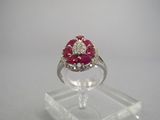 un gros plan d'une bague sertie d'un diamant et d'un rubis, posée sur un socle transparent