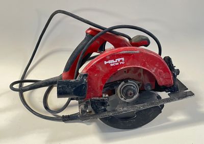 une scie circulaire rouge posée sur une surface blanche