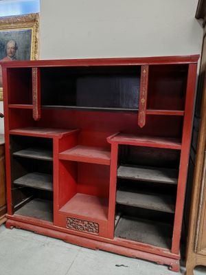 une armoire rouge avec des étagères et un tableau accroché au mur