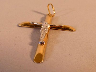 une croix en or sertie d'un diamant, posée sur une table