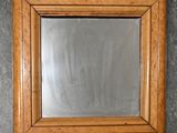 un gros plan d'un miroir accroché au mur, avec un cadre en bois