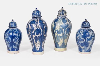 quatre vases bleus et blancs sont alignés sur un fond blanc