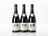 three bottles of wine are lined up on a white surface