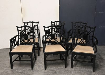 four black chairs with beige cushions sit in front of a white wall