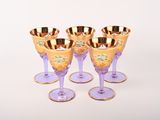 verres à vin violets et dorés, avec des bords dorés, posés sur une surface blanche