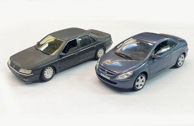 two toy cars sitting next to each other on a white surface