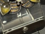 a close up of a silver bracelet with a yellow stone on it