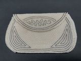 a white beaded purse on a black background