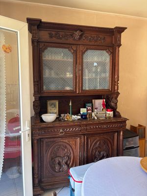 a wooden china cabinet in the corner of the room