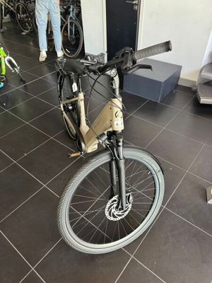 un vélo posé dans une pièce où des gens sont debout tout autour