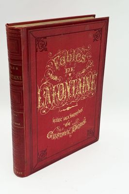 un livre rouge avec des lettres dorées posé sur une surface blanche