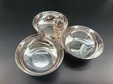 three silver plated dishes on a black table with a black background