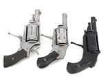 three old revolvers are sitting side by side on a white surface