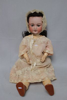 an antique doll sitting on a white surface wearing a dress and bonnet