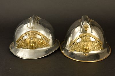 une paire de casques de pompier argentés et dorés sur fond noir